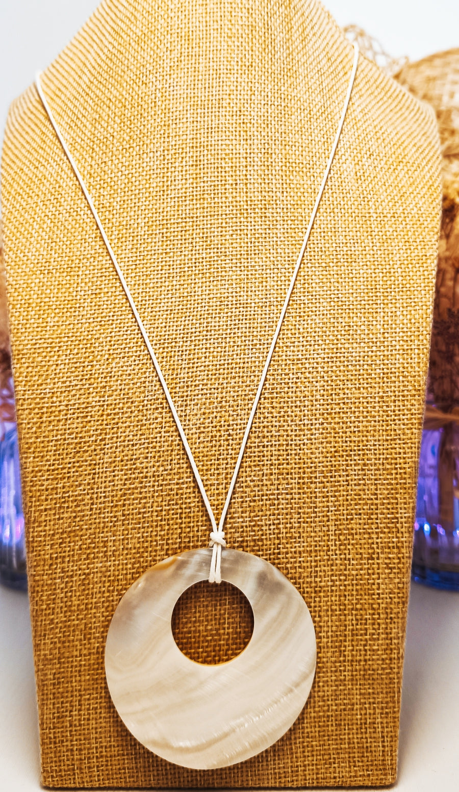 Collier : cordon ciré blanc avec  pendentif nacre de 6,3cm. Longueur 57 cm